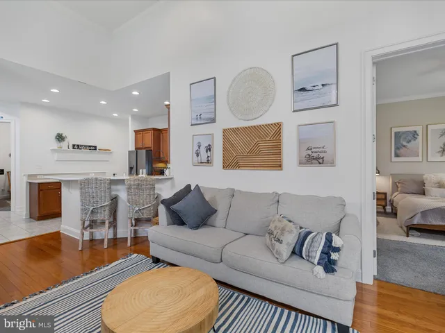 a living room with furniture wooden floor and kitchen view