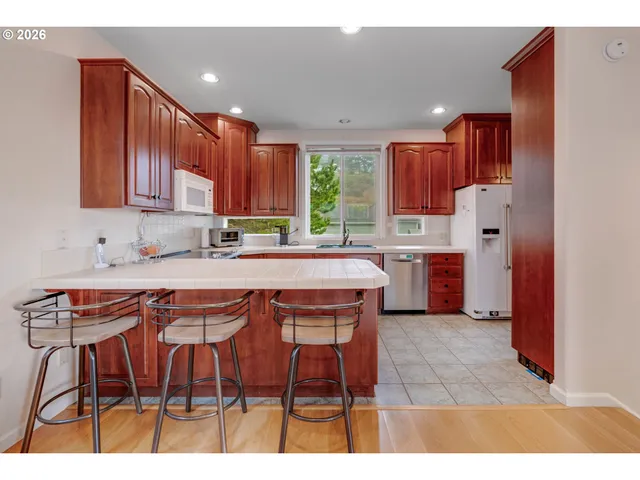 a kitchen with stainless steel appliances granite countertop a table chairs sink refrigerator and cabinets