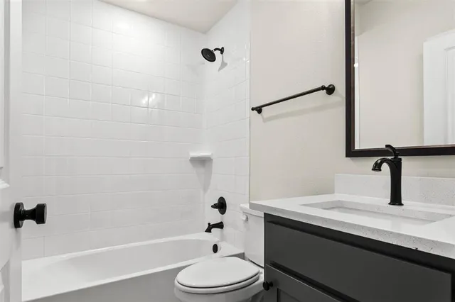 a bathroom with a granite countertop bathtub shower sink vanity and toilet