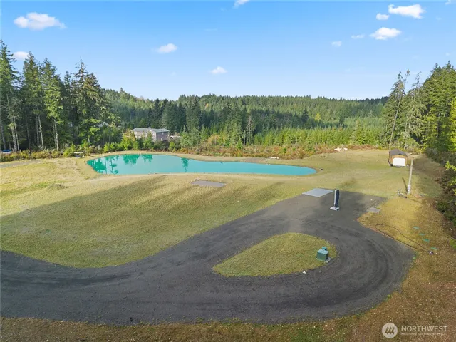 a view of a swimming pool with a yard and trees in the background