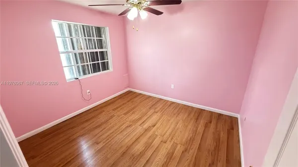 a view of empty room with a window and wooden floor