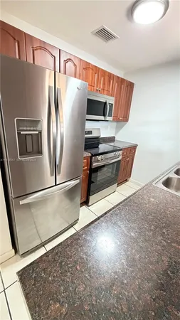 a view of kitchen with stainless steel appliances wooden floor and a refrigerator