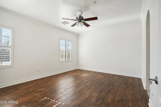 an empty room with wooden floor fan and windows