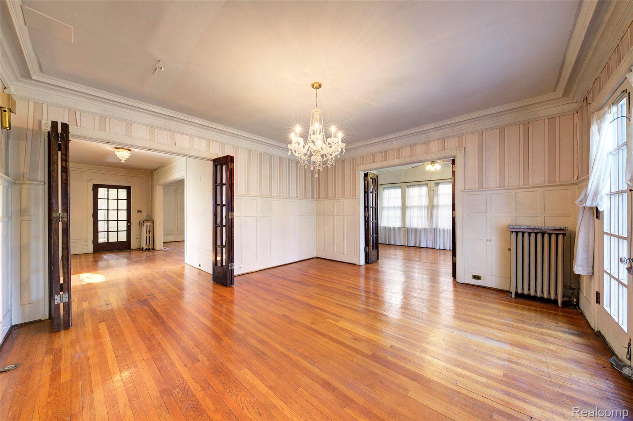 121 Longfellow Street Detroit, MI 48202 - Photo 23 of 87 Unfurnished room featuring wallpapered walls, plenty of natural light, light wood-style floors, wainscoting, and a chandelier