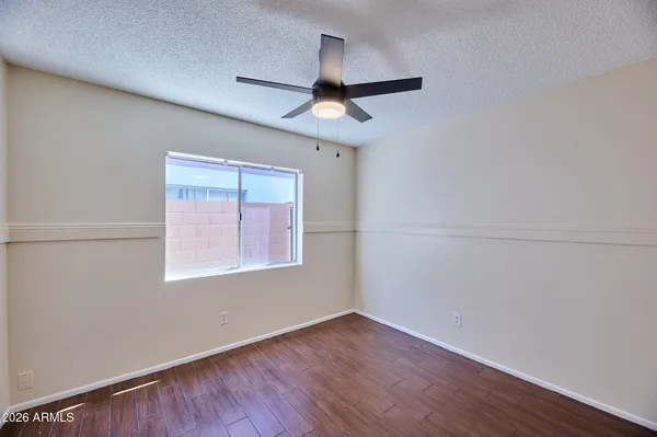 an empty room with wooden floor ceiling fan and windows