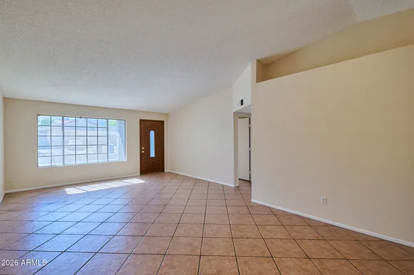 a view of an empty room with window and chandelier fan
