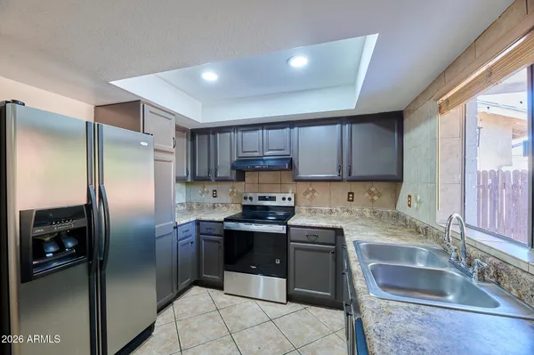 a kitchen with granite countertop stainless steel appliances cabinets a sink and a large window