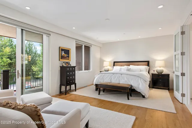 a bedroom with a bed and a dresser with wooden floor
