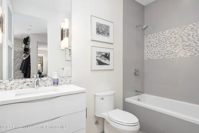 a bathroom with a toilet a sink a mirror a lamp a bathtub and vanity