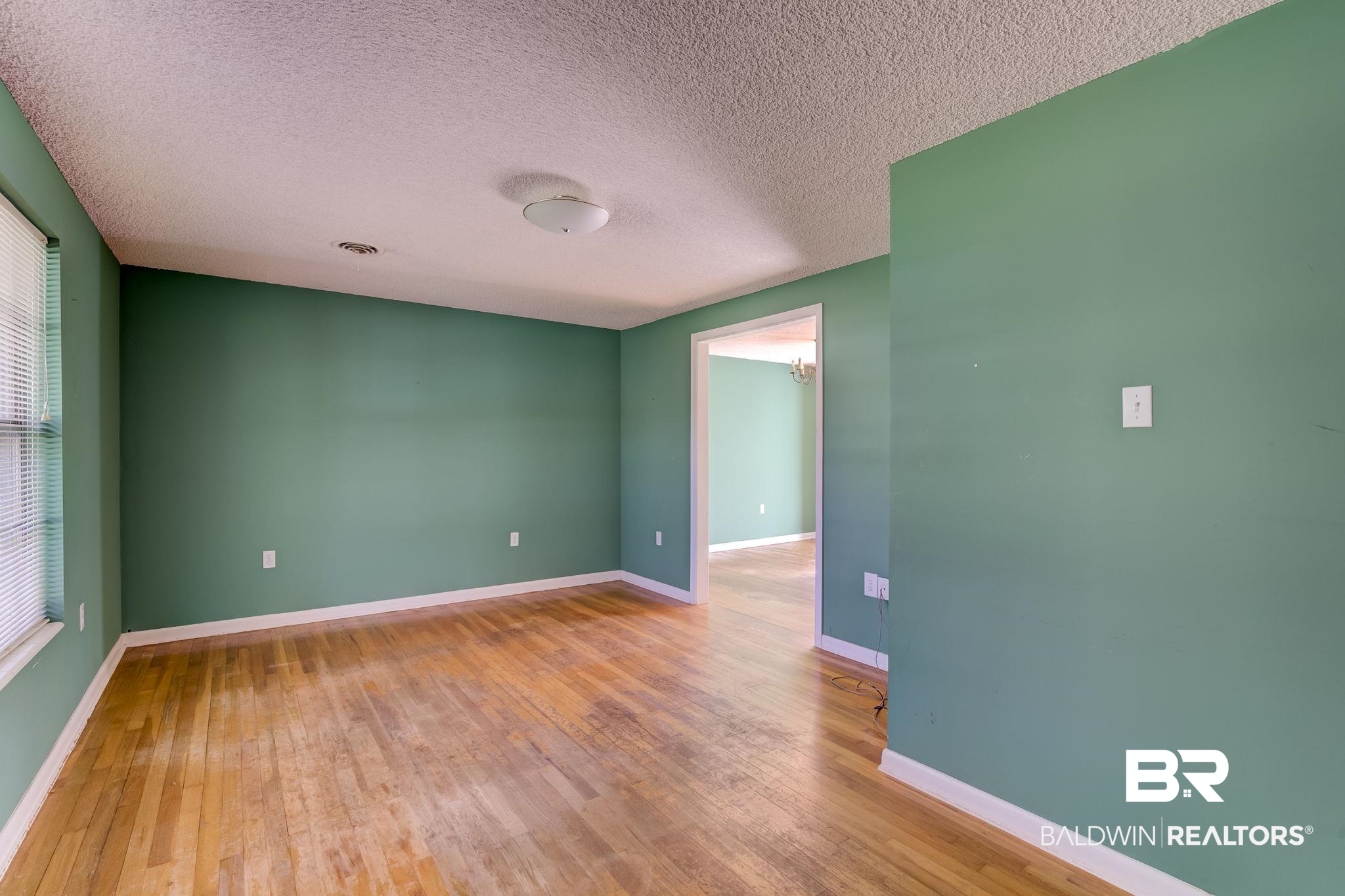 606 East Myrtle Avenue Foley, AL 36535 - Photo 4 of 24 Spare room with a textured ceiling, hardwood / wood-style flooring, and an inviting chandelier