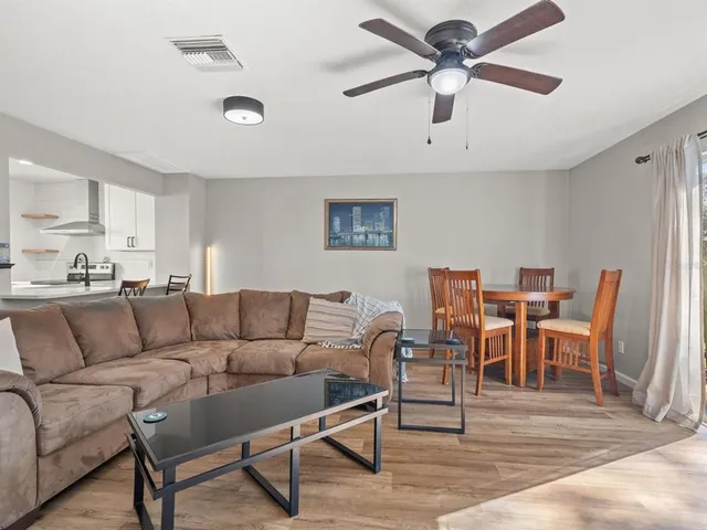 a living room with furniture kitchen view and a chandelier