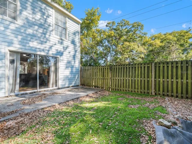 a view of a backyard with plants and large trees