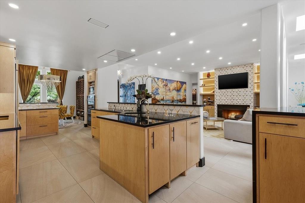 308 North Broadway Road Azle, TX 76020 - Photo 13 of 31 The kitchen features light wood cabinetry, black countertops, and a central island with a sink