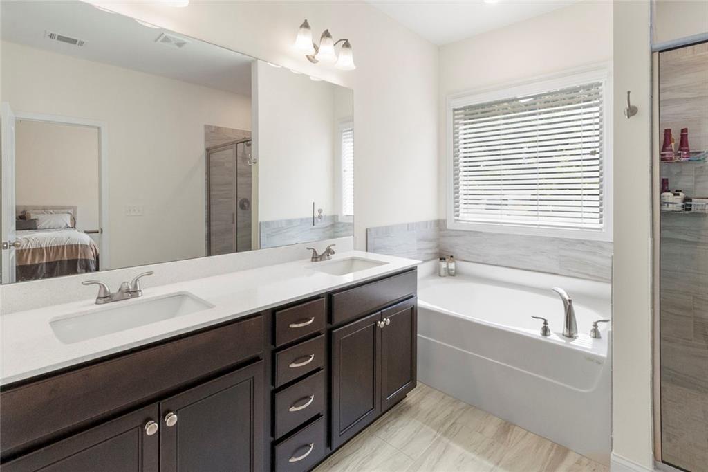5437 Maple Grv Lane Flowery Branch, GA 30542 - Photo 25 of 27 a bathroom with a tub a sink double vanity and a mirror