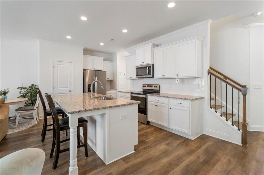 5437 Maple Grv Lane Flowery Branch, GA 30542 - Photo 5 of 27 a kitchen with kitchen island granite countertop wooden floor a center island stainless steel appliances cabinets and a counter top space