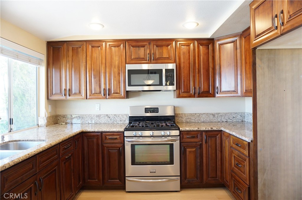 19584 Shadow Glen Circle Porter Ranch, CA 91326 - Photo 12 of 72 a kitchen with granite countertop a stove top oven microwave and cabinets