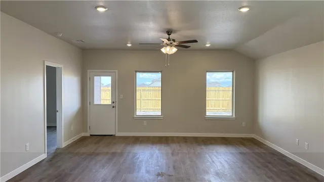 a view of an empty room with a window and wooden floor