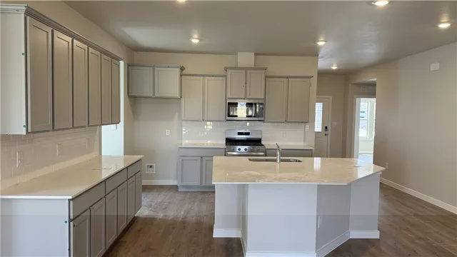 a kitchen with stainless steel appliances granite countertop a stove a sink a refrigerator and a microwave