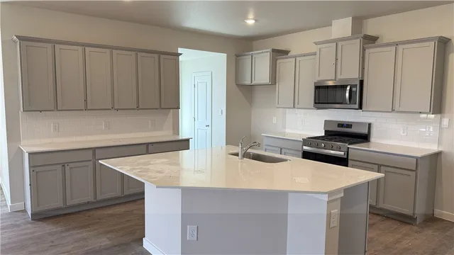 a kitchen with stainless steel appliances a stove a sink a microwave and refrigerator