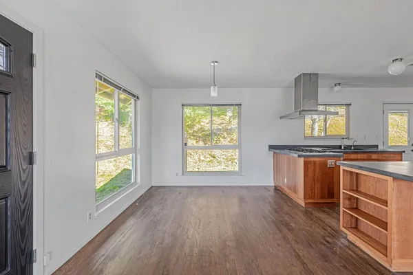 a kitchen with stainless steel appliances granite countertop wooden floors wooden cabinets and sink