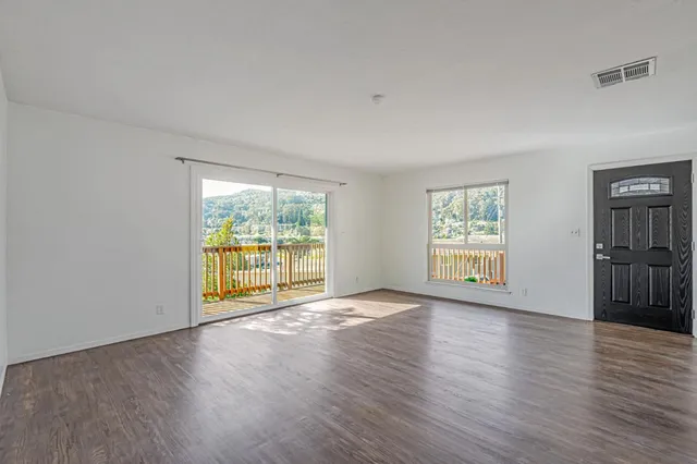 a view of an empty room with a window and wooden floor