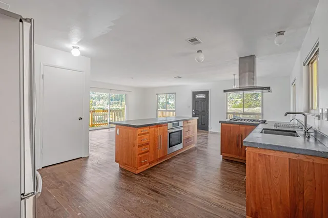 a kitchen with stainless steel appliances granite countertop a sink stove and wooden floor