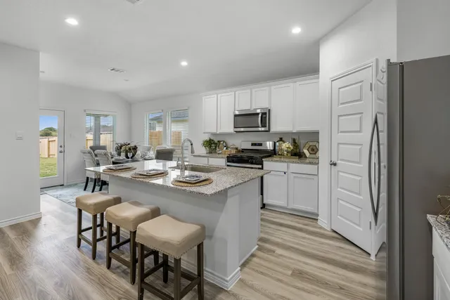 a kitchen with kitchen island a white counter top space a refrigerator cabinets and a dining table
