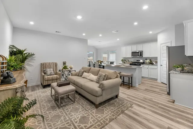 a living room with furniture and a dining table with kitchen view