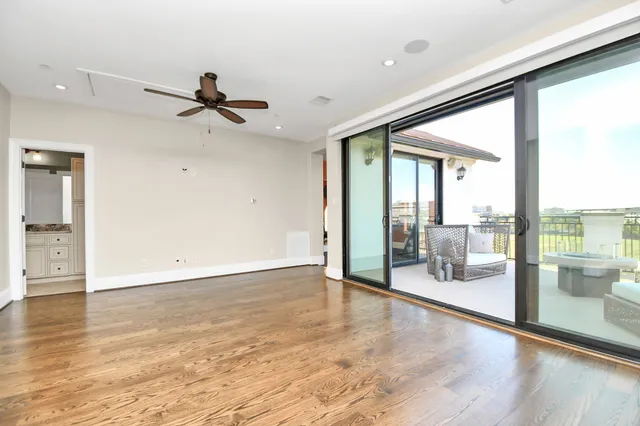 a view of an empty room with window a ceiling fan and wooden floor