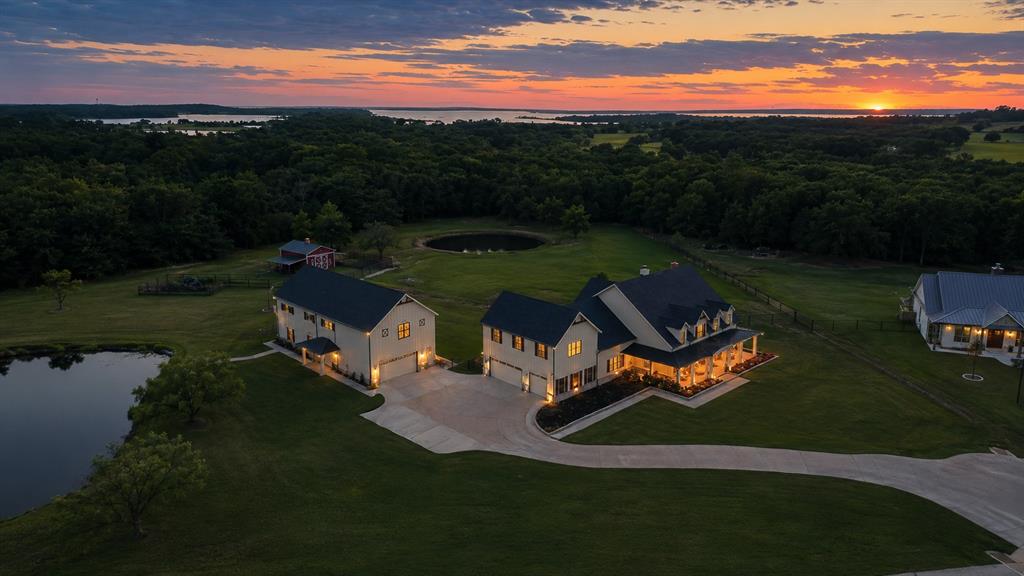 985 Vest Lane Pilot Point, TX 76258 - Photo 6 of 40 Expansive property featuring a main residence with a covered front porch, a separate guest house, and a detached auxiliary building