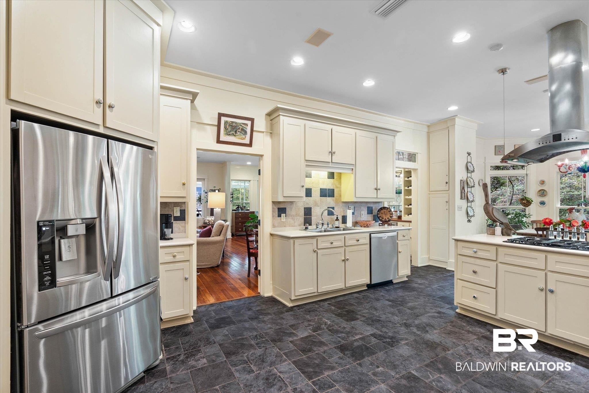 2300 Burgett Road Mobile, AL 36605 - Photo 11 of 40 Kitchen with stainless steel appliances, island exhaust hood, stone finish floors, hanging light fixtures, and decorative backsplash