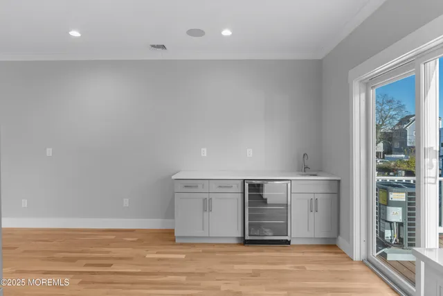 a view of kitchen and empty room with wooden floor and windows