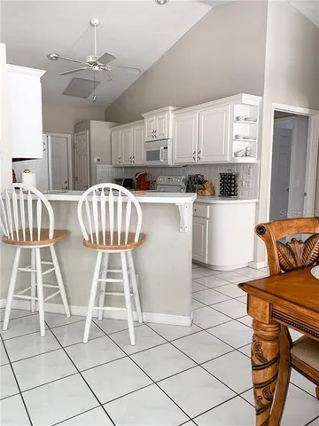 a kitchen with stainless steel appliances kitchen island granite countertop a refrigerator a stove a sink dishwasher and white cabinets with wooden floor