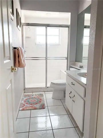 a bathroom with a granite countertop sink toilet a mirror and next to a window