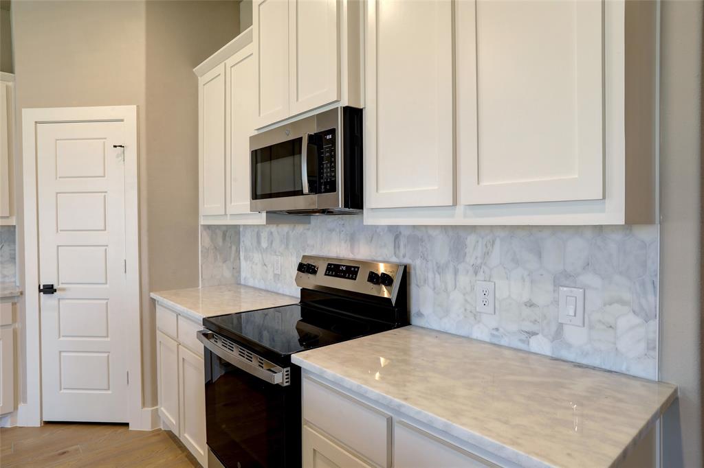 204 Pennington Road Josephine, TX 75173 - Photo 9 of 25 a kitchen with white cabinets and black appliances