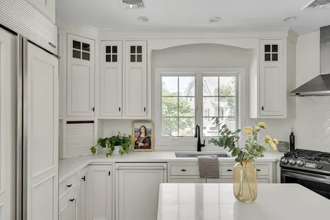 a kitchen with stainless steel appliances a white refrigerator a sink and white cabinets