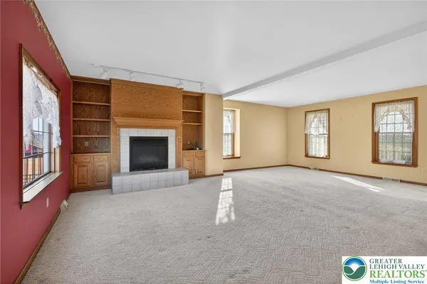 an empty room with windows and fireplace