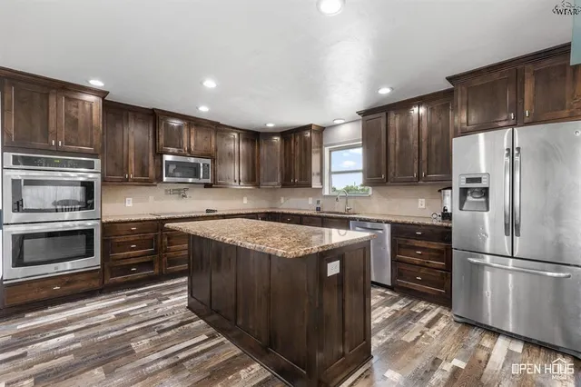 a kitchen with stainless steel appliances granite countertop a table chairs sink refrigerator and microwave