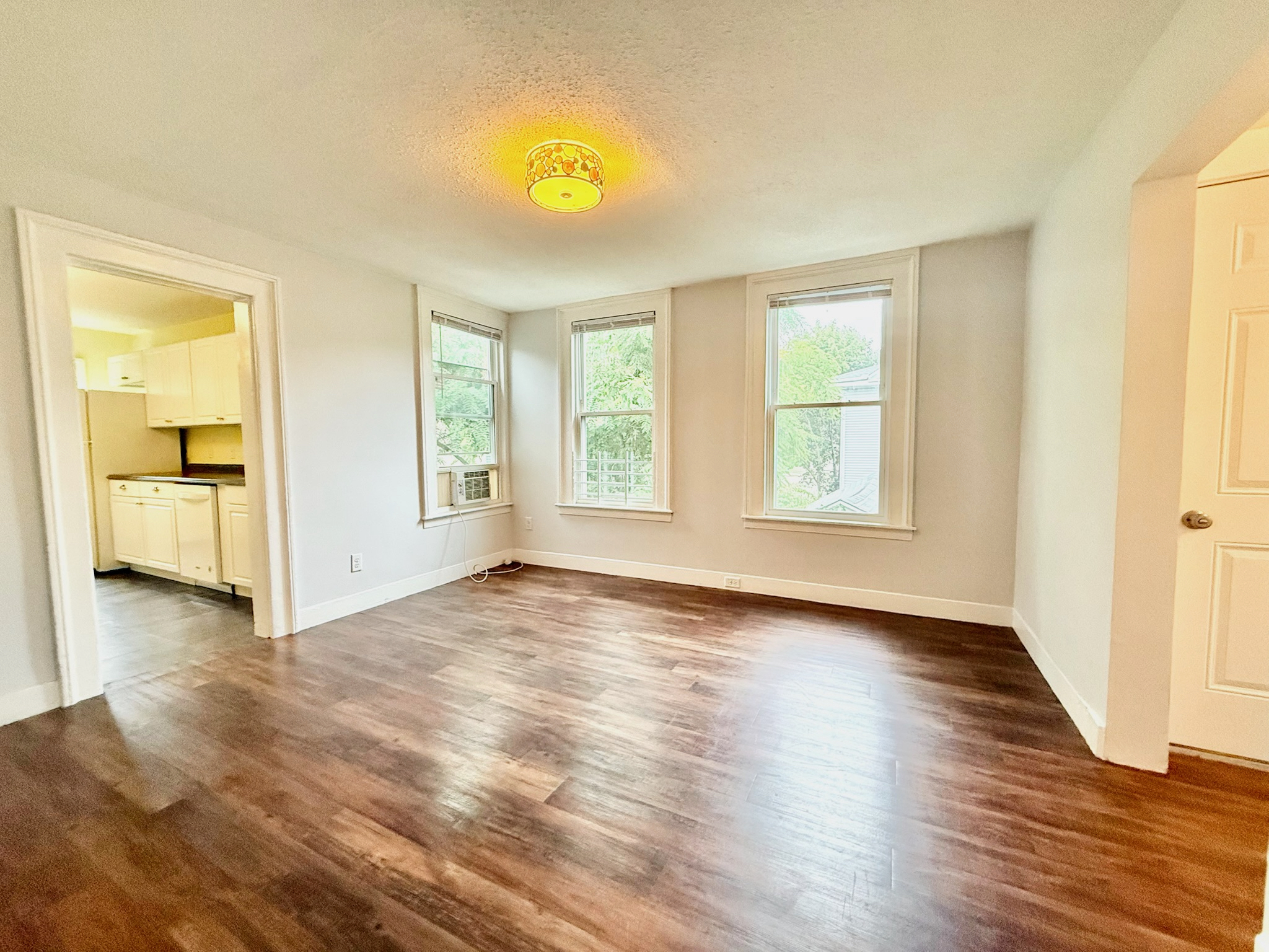 a view of an empty room with window and wooden floor