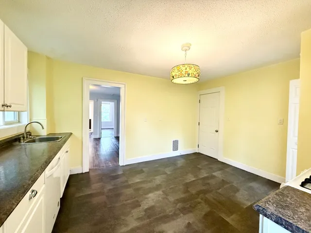 a view of a kitchen with kitchen island a sink stainless steel appliances wooden floor and a window