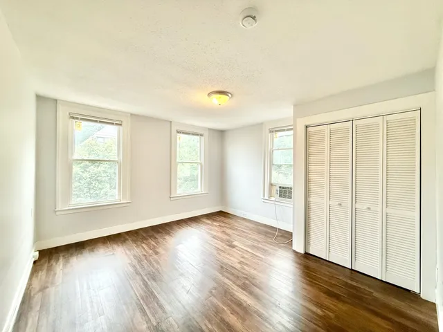 an empty room with wooden floor and windows
