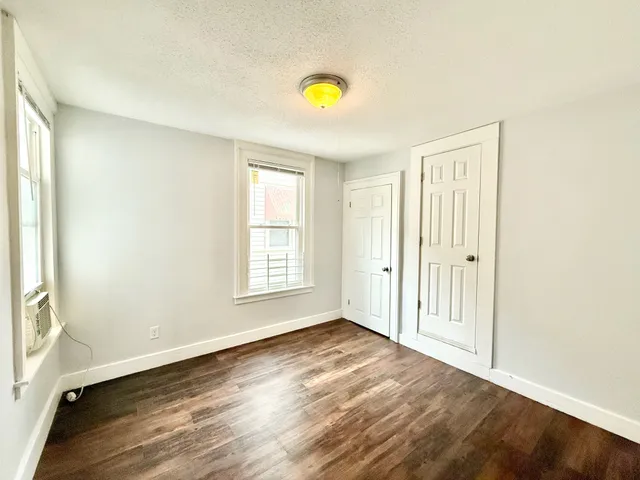 an empty room with wooden floor and natural light