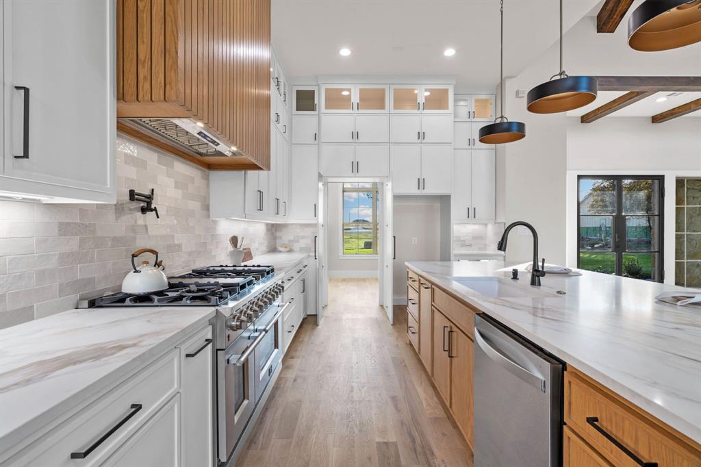 559 Aermotor Loop Weatherford, TX 76085 - Photo 11 of 39 a kitchen with stainless steel appliances granite countertop a sink a stove and a wooden floors