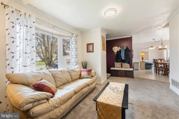 a living room with furniture and a large mirror next to a window
