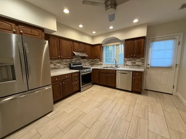 a kitchen with stainless steel appliances granite countertop a refrigerator a sink a stove top oven and cabinets