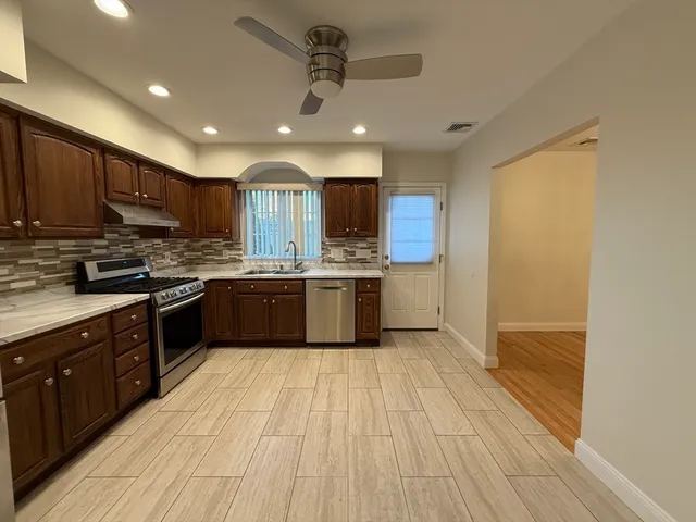 a large kitchen with stainless steel appliances granite countertop a stove a sink dishwasher and a refrigerator with wooden floor