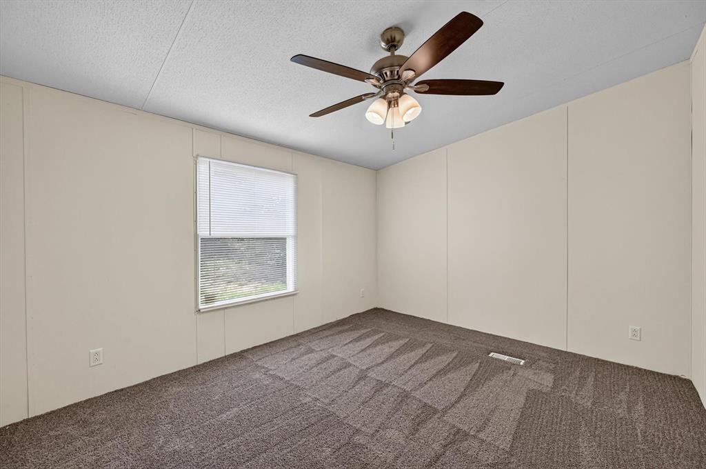 13405 Wheat Road Venus, TX 76084 - Photo 19 of 32 Room featuring neutral wall paneling, textured carpeting, and a ceiling fan with integrated lighting