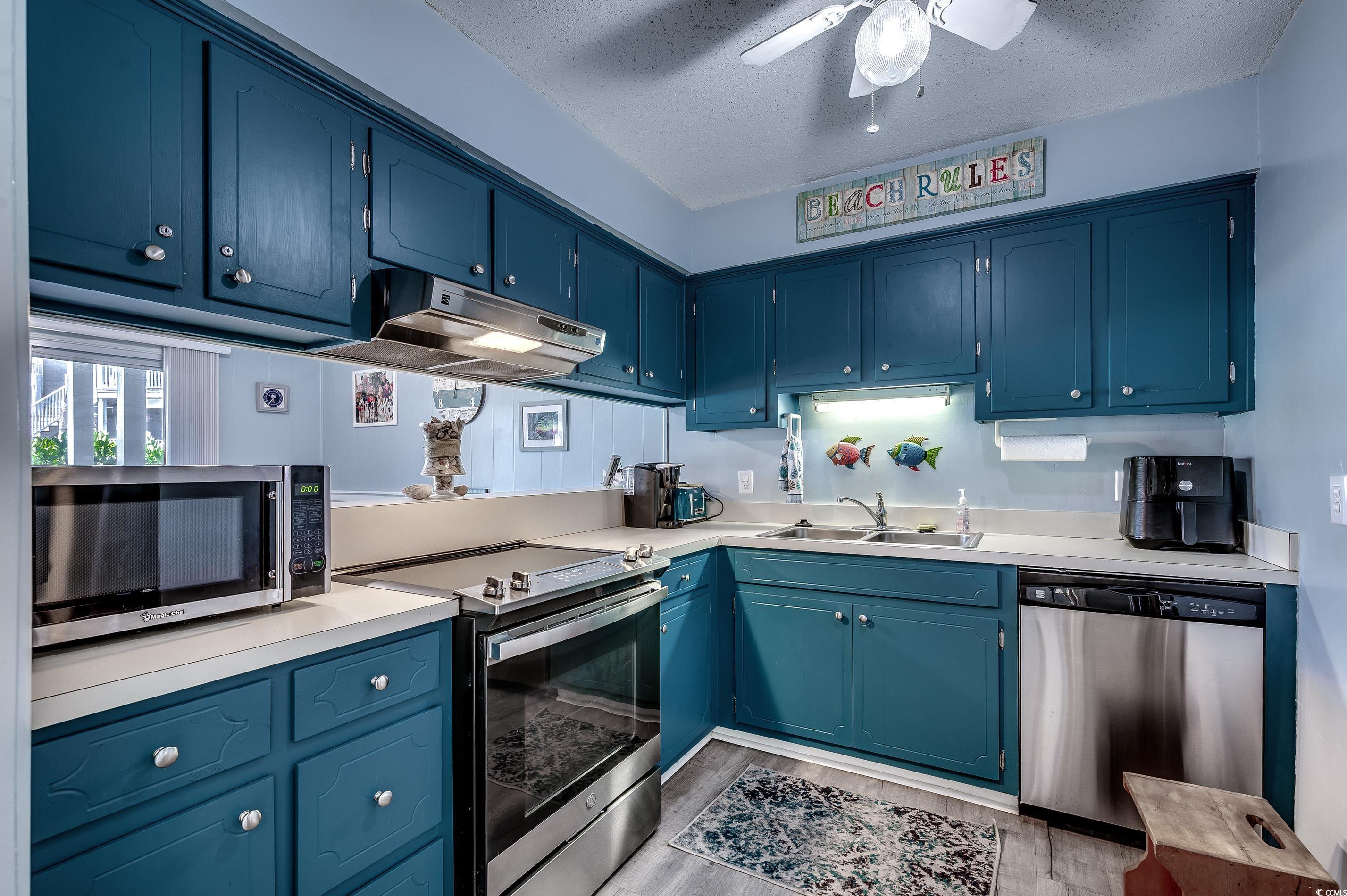 416 North Ocean Boulevard, Unit B7 Surfside Beach, SC 29575 - Photo 11 of 30 Kitchen with appliances with stainless steel finishes, light wood finished floors, a textured ceiling, a ceiling fan, and light countertops