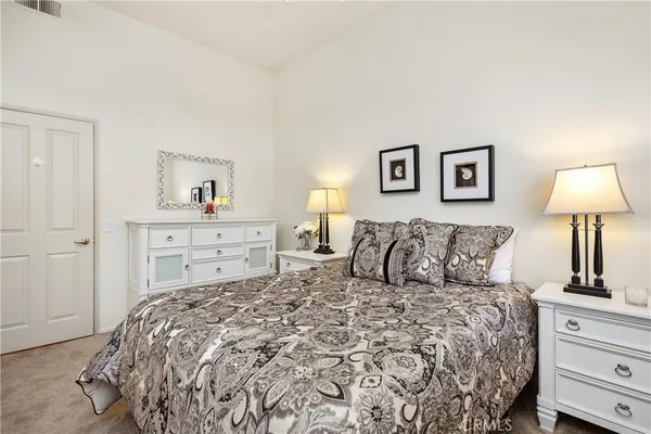 a bedroom with a bed and a lamp on dresser