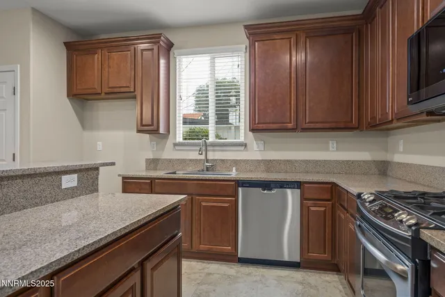 a kitchen with granite countertop a sink a stove and cabinets